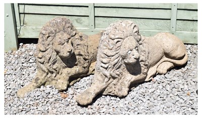 Lot 607 - Pair of composite stone garden lions in recumbent posture