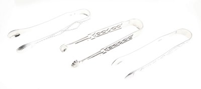 Lot 118 - Three pairs of George III silver sugar tongs, two with bright cut decoration