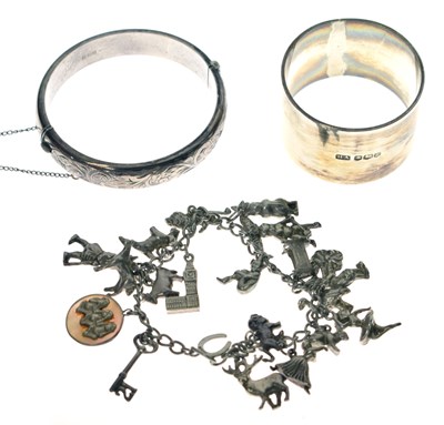 Lot 204 - Silver napkin ring, silver hinged bangle and a silver charm bracelet