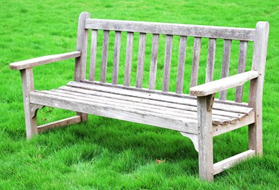 Lot 537 - Late 20th century teak two-seater garden bench of slatted design with flat arms