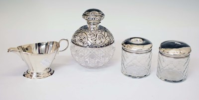 Lot 243 - George V silver cream jug, together with three silver-topped dressing table jars