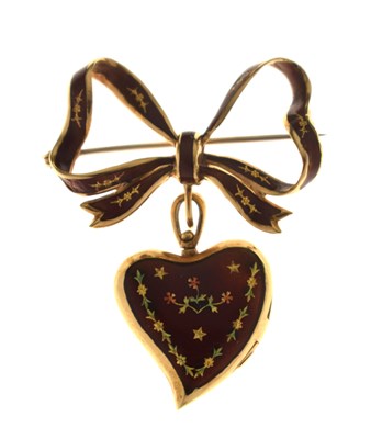 Lot 45 - Yellow metal (750) and red enamel decorated heart-shaped locket on a tied bow brooch fitting