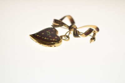 Lot 45 - Yellow metal (750) and red enamel decorated heart-shaped locket on a tied bow brooch fitting