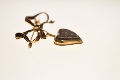 Lot 45 - Yellow metal (750) and red enamel decorated heart-shaped locket on a tied bow brooch fitting