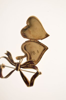Lot 45 - Yellow metal (750) and red enamel decorated heart-shaped locket on a tied bow brooch fitting