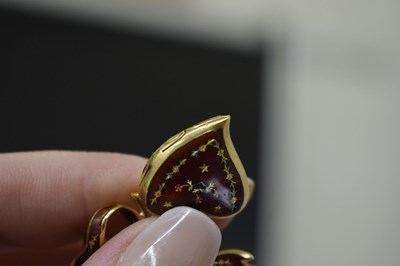 Lot 45 - Yellow metal (750) and red enamel decorated heart-shaped locket on a tied bow brooch fitting