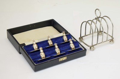 Lot 96 - George V silver toast rack, together with a set of six silver-plated novelty menu holders