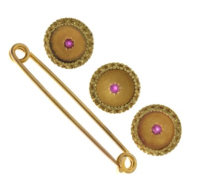 Lot 21 - Three yellow metal (9ct) ruby-set buttons