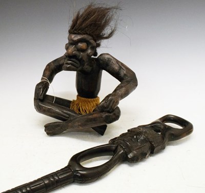 Lot 265 - Ethnographica - Carved seated figure wearing a grass skirt, together with a carved stick