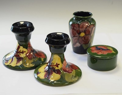 Lot 384 - Moorcroft - Pair of  Hibiscus pattern candlesticks, vase and lidded pot